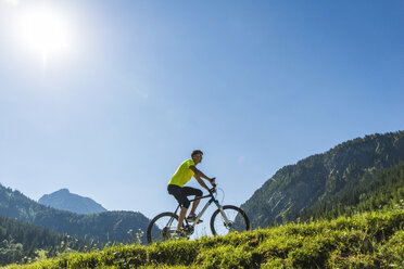 Austria, Tyrol, Tannheim Valley, young man on mountain bike in alpine landscape - UUF004933