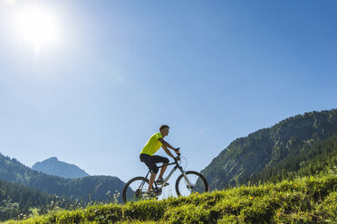 Österreich, Tirol, Tannheimer Tal, junger Mann auf Mountainbike in alpiner Landschaft - UUF004933