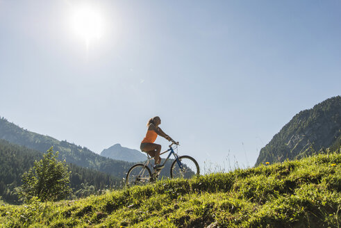 Österreich, Tirol, Tannheimer Tal, junge Frau auf Mountainbike in alpiner Landschaft - UUF004934