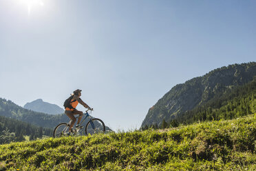 Österreich, Tirol, Tannheimer Tal, junge Frau auf Mountainbike in alpiner Landschaft - UUF004936