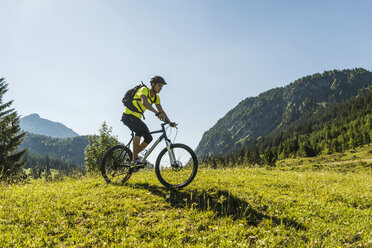 Austria, Tyrol, Tannheim Valley, young man on mountain bike in alpine landscape - UUF004939