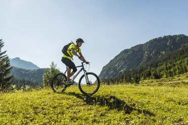 Österreich, Tirol, Tannheimer Tal, junger Mann auf Mountainbike in alpiner Landschaft - UUF004939