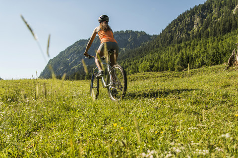 Österreich, Tirol, Tannheimer Tal, junge Frau auf Mountainbike in alpiner Landschaft, lizenzfreies Stockfoto