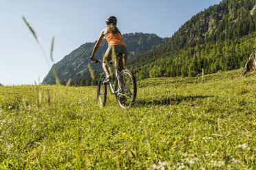 Österreich, Tirol, Tannheimer Tal, junge Frau auf Mountainbike in alpiner Landschaft - UUF004940
