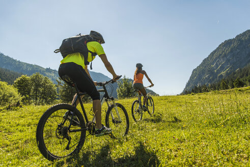 Austria, Tyrol, Tannheim Valley, young couple on mountain bikes in alpine landscape - UUF004981