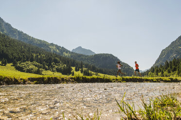 Österreich, Tirol, Tannheimer Tal, junges Paar joggt am Flussufer - UUF004949