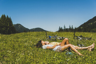 Österreich, Tirol, Tannheimer Tal, junges Paar mit Mountainbikes auf einer Wiese - UUF004965