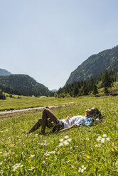 Österreich, Tirol, Tannheimer Tal, junge Frau entspannt sich auf einer Wiese - UUF004966