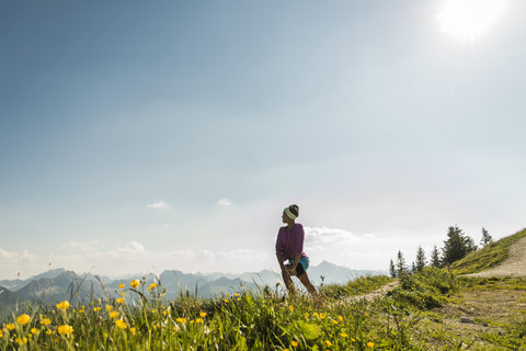 Österreich, Tirol, Tannheimer Tal, junge Frau steht in einer Berglandschaft und betrachtet die Aussicht, lizenzfreies Stockfoto