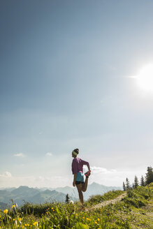 Österreich, Tirol, Tannheimer Tal, junge Frau streckt sich in den Bergen - UUF004975