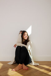 Smiling young woman sitting on floor - CHAF000594