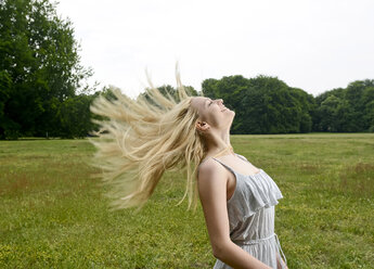 Young woman tossing her hair on a meadow - BFRF001318