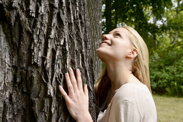 Young woman leaning on tree trunk - BFRF001330