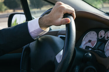 Hand eines Geschäftsmannes am Lenkrad seines Autos - ABZF000085