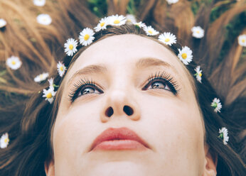 Junge Frau im Gras liegend mit Gänseblümchen im Haar, Nahaufnahme - GEMF000279