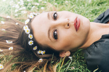 Portrait of young woman lying on grass with daisies in her hair - GEMF000280