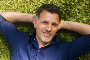 Mature man lying on grass, smiling - CHAF000751