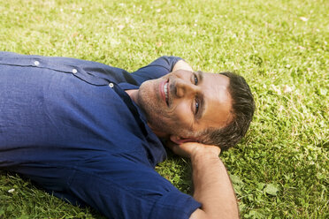 Älterer Mann im Gras liegend, lächelnd - CHAF000752