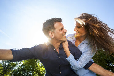 Happy couple in park pretending to fly - CHAF000758