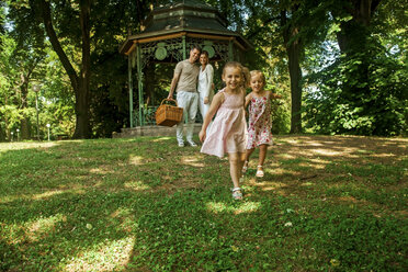 Glückliche Familie im Park, Eltern tragen Picknickkorb - CHAF000765