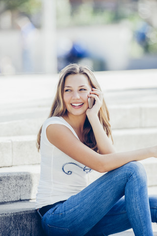 Porträt eines lächelnden Teenagers, der mit einem Smartphone telefoniert, lizenzfreies Stockfoto