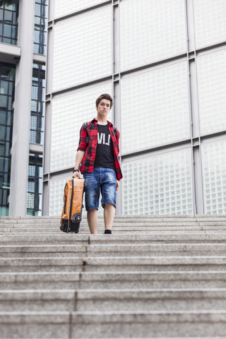 Germany, Berlin, teenage boy with suitcase walking downstairs stock photo