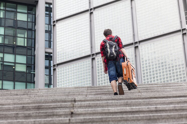 Germany, Berlin, teenage boy with suitcase walking upstairs - MMFF000876