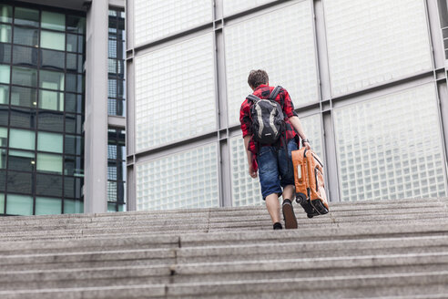 Deutschland, Berlin, Jugendlicher mit Koffer geht eine Treppe hinauf - MMFF000876