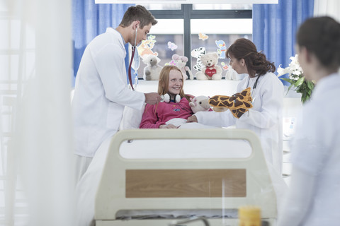 Ärzte untersuchen ein Mädchen im Krankenhausbett, lizenzfreies Stockfoto