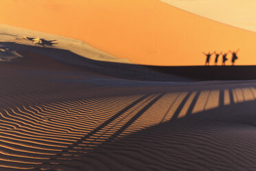 Namibia, Namib-Wüste, Namib-Naukluft-Nationalpark, Silhouetten von vier Touristen auf einer Wüstendüne - FOF008173