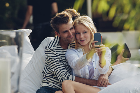 Junge Frau macht ein Selfie von sich und ihrem Freund in einem Straßencafé, lizenzfreies Stockfoto