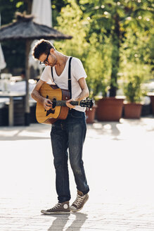 Junger Mann spielt Gitarre auf der Straße - CHAF000816