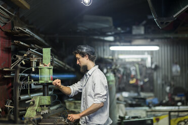 Junger Mann mit Kinnbart bei der Arbeit im alternativen Technikraum - SGF001779