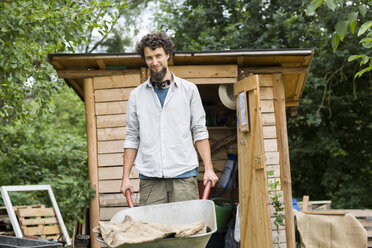 Young man with wheelbarrow in an urban garden - SGF001758