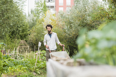 Young man with wheelbarrow in an urban garden - SGF001759