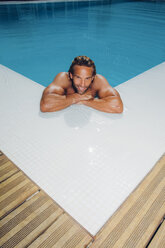 Porträt eines lächelnden Mannes im Schwimmbad, der sich auf den Beckenrand stützt - CHAF000637