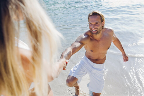 Spanien, Mallorca, Frau zieht an der Hand eines Mannes am Strand - CHAF000658