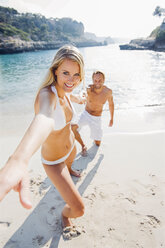 Spanien, Mallorca, Frau zieht an der Hand eines Mannes am Strand - CHAF000659