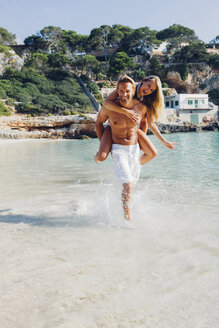 Spanien, Mallorca, Mann nimmt seine Freundin am Meer huckepack - CHAF000662