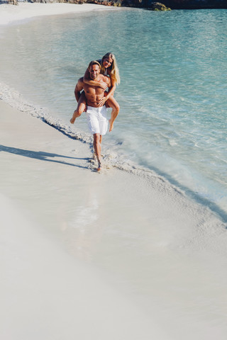 Spanien, Mallorca, Mann nimmt seine Freundin am Meer huckepack, lizenzfreies Stockfoto