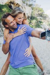 Couple filming themselves with a camcorder at the beach - CHAF000678