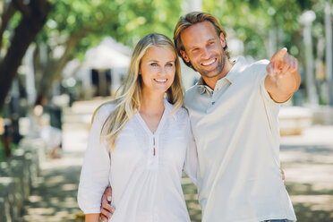Smiling couple outdoors with man pointing finger - CHAF000689
