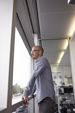 Mann im Büro schaut aus dem Fenster, lizenzfreies Stockfoto