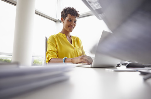 Junge Frau benutzt Laptop im Büro, lizenzfreies Stockfoto