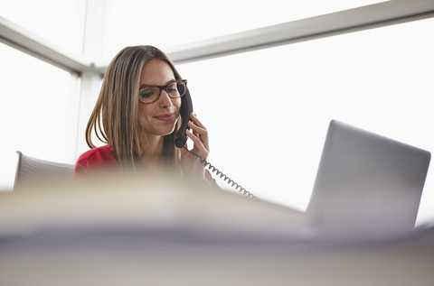 Junge Frau im Büro am Telefon, lizenzfreies Stockfoto