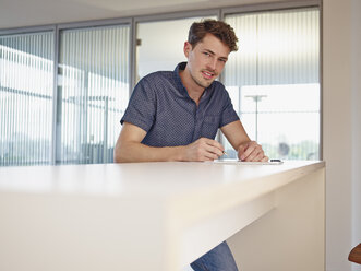 Young man in office writing at counter - RHF000972