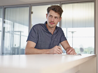 Young man in office writing at counter - RHF000973