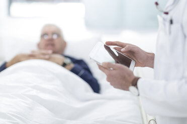 Nahaufnahme eines Arztes, der neben einem Patienten ein digitales Tablet benutzt - ZEF005989