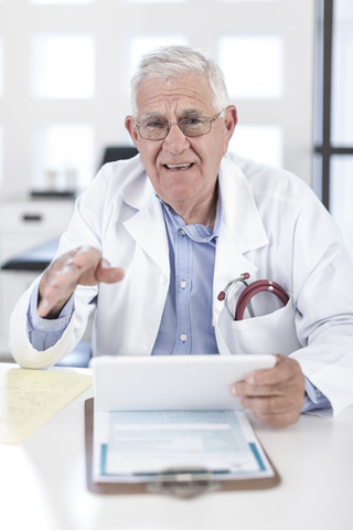 Ernster Oberarzt am Schreibtisch, der eine Patientenakte bespricht, lizenzfreies Stockfoto