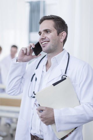 Lächelnder Arzt im Krankenhaus am Telefon, lizenzfreies Stockfoto